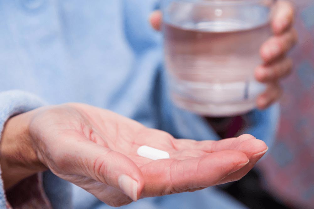 hand met pil en glas water