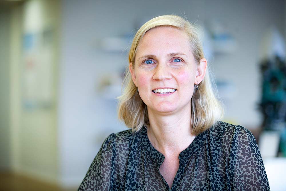 portretfoto van Marloes, een witte vrouw met halflang lichtblond haar. Ze glimlacht de camera in. Ze draagt een donkerblauw met zwart stippenblousje.