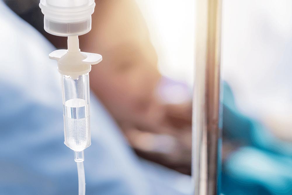 infuus op voorgrond met patiënt op achtergrond